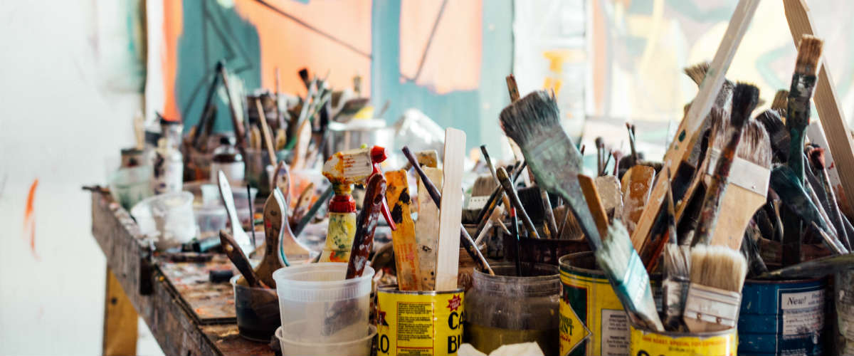 messy table full of paint brushes